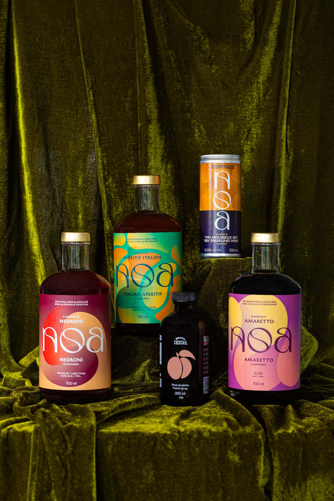 NOA Dragon Kit bottles and can on green velvet with a Monsieur Cocktail syrup